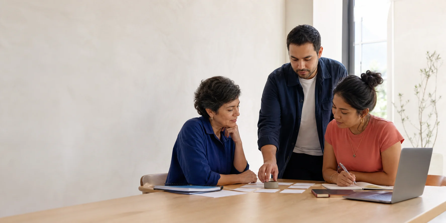 Personas colaborando con materiales de trabajo y una computadora portátil